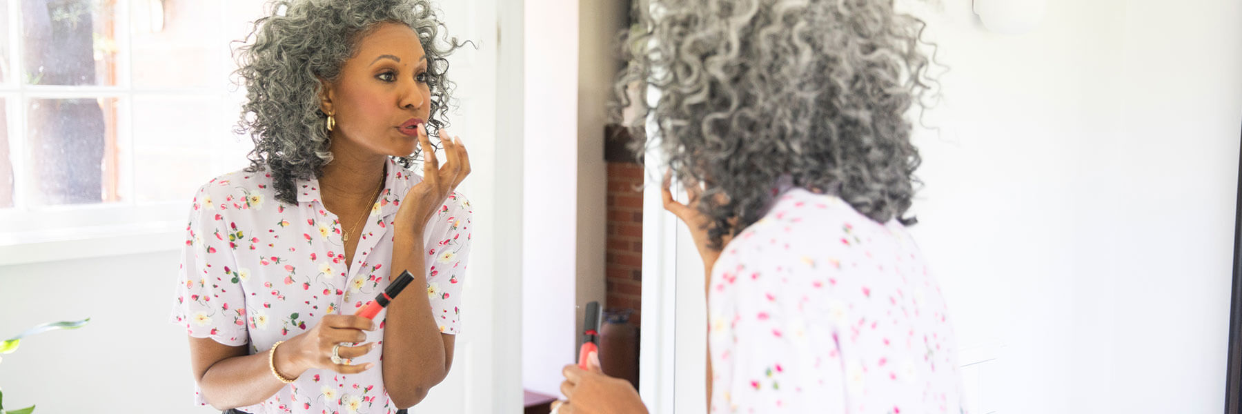 Older woman applying makeup in a mirror