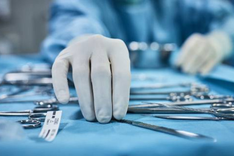 Gloved hands reaching for surgical instruments